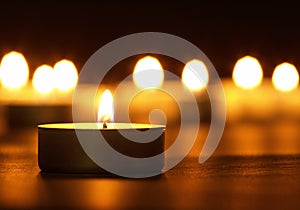 Burning candles with a yellow flame on a black table with a blurred background. Christmas candles. Lighted candles at night in the