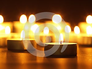 Burning candles with a yellow flame on a black table with a blurred background. Christmas candles. Lighted candles at night in the