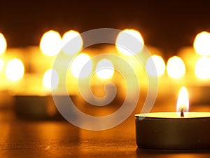 Burning candles with a yellow flame on a black table with a blurred background. Christmas candles. Lighted candles at night in the