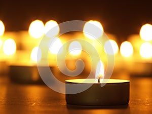 Burning candles with a yellow flame on a black table with a blurred background. Christmas candles. Lighted candles at night in the