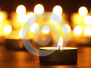 Burning candles with a yellow flame on a black table with a blurred background. Christmas candles. Lighted candles at night in the