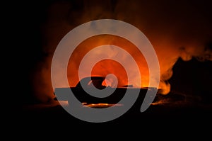 Burning car on a dark background. Car catching fire, after act of vandalism or road indicent