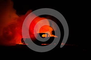 Burning car on a dark background. Car catching fire, after act of vandalism or road indicent