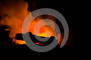 Burning car on a dark background. Car catching fire, after act of vandalism or road indicent