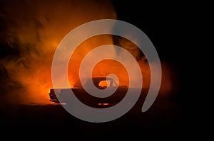 Burning car on a dark background. Car catching fire, after act of vandalism or road indicent