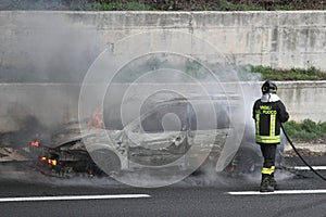 Burning car with firefighters