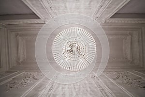 Burning chandelier on ceiling in narrow room, view photo