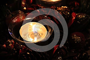 Burning Christmas candle, decorated with tree cones and ornaments. Shot with a festive mood