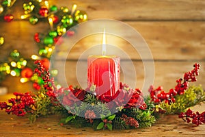 Burning Christmas red candle and  festive Christmas arrangement on a wooden table