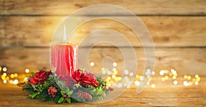 Burning Christmas red candle and  festive Christmas arrangement on a wooden table