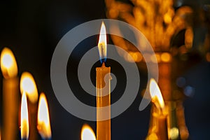 Burning church wax candles in a candlestick, closeup. Concept of religion, faith, rituals, monasteries, temples, churches, rituals