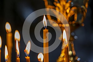 Burning church wax candles in a candlestick, closeup. Concept of religion, faith, rituals, monasteries, temples, churches, rituals