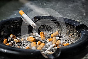 Burning Cigarette on Dirty Ashtray