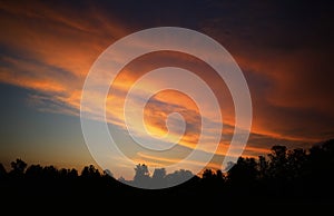 Burning clouds over the sunset forest background