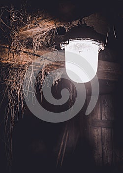 A burning electric light bulb in an old barn