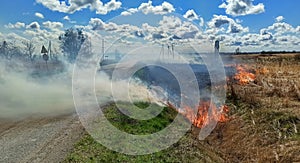 Burning field close to a road, dry grass on fire