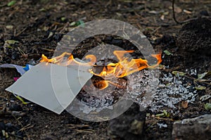 Burning in the fire of a torn notebook. The cover and the multi-colored sheets burn into gray ash
