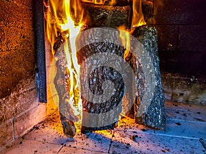 Burning firewood in the fireplace closeup, glowing logs, fire and flames