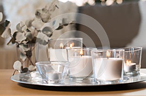 Burning fragrance candles on table at cozy home