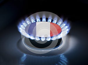 Burning gas burner of a home stove in the middle of which is the flag of the country of France. Gas import and export