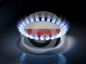 Burning gas burner of a home stove in the middle of which is the flag of the country of Poland. Gas import and export