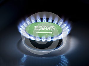 Burning gas burner of a home stove in the middle of which is the flag of the country of Saudi Arabia. Gas import and export