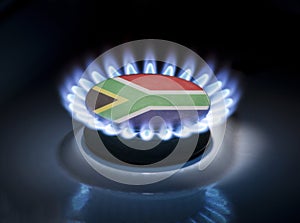 Burning gas burner of a home stove in the middle of which is the flag of the country of South Africa. Gas import and export