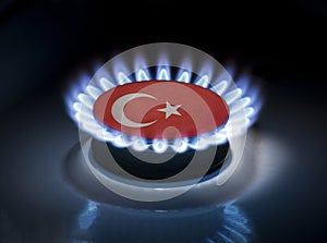 Burning gas burner of a home stove in the middle of which is the flag of the country of Turkey. Gas import and export delivery