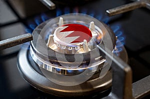 A burning gas burner of a home stove, in the middle of which a flag is depicted - Bahrain