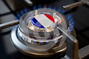 A burning gas burner of a home stove, in the middle of which a flag is depicted - France