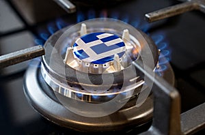 A burning gas burner of a home stove, in the middle of which a flag is depicted - Greece