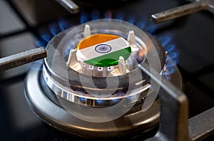 A burning gas burner of a home stove, in the middle of which a flag is depicted - India