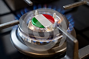 A burning gas burner of a home stove, in the middle of which a flag is depicted - Italy