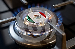 A burning gas burner of a home stove, in the middle of which a flag is depicted - Mexico