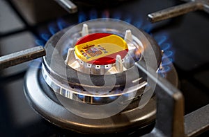 A burning gas burner of a home stove, in the middle of which a flag is depicted - Spain