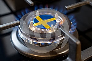 A burning gas burner of a home stove, in the middle of which a flag is depicted - Sweden