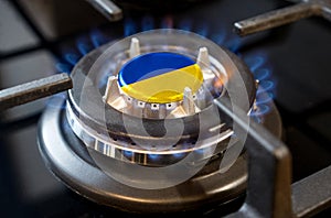 A burning gas burner of a home stove, in the middle of which a flag is depicted - Ukraine