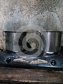 a burning gas stove and on top of which are placed two pots of water?