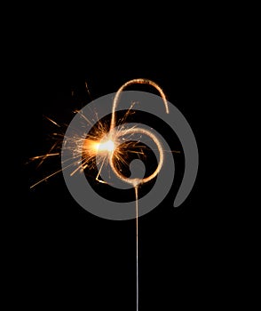 Burning golden sparkler in shape of number six, digit 6, isolated on black