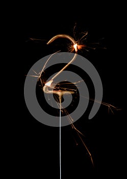 Burning golden sparkler in shape of number two, digit 2, isolated on black