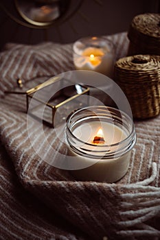 Burning hand-made candle with wooden wick in glass jar