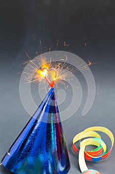 Burning heart on party hats, black background, birthday card