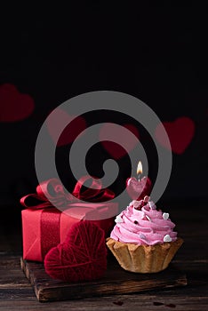 Burning heart shaped candle on cupcake and gift, Valentine`s Day concept