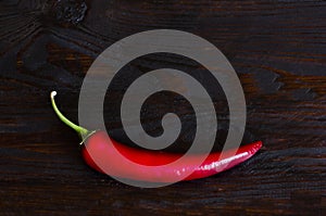 Burning hot vibrant red mexican chilli pepper. Hot spicy red chili peppers on a dark wooden background.