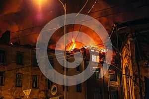 Burning house at night, roof of building in flames of fire and smoke