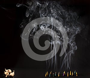 Burning incense cones with intense smoke on black background