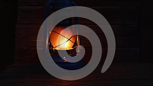 Burning kerosene lamp with a wooden background.