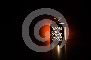 Burning lantern in the dark. Ornamental lantern with burning candle glowing at night. Wth a lot of empty space. Red orange fire ba