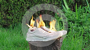 Burning leather sports shoes. Sneakers or gym shoes on fire stand on the Stump.