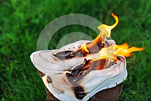 Burning leather sports shoes. Sneakers or gym shoes on fire stand on the Stump.